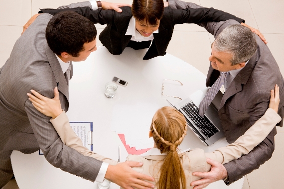 Photo of happy business partners embracing each other over workplace